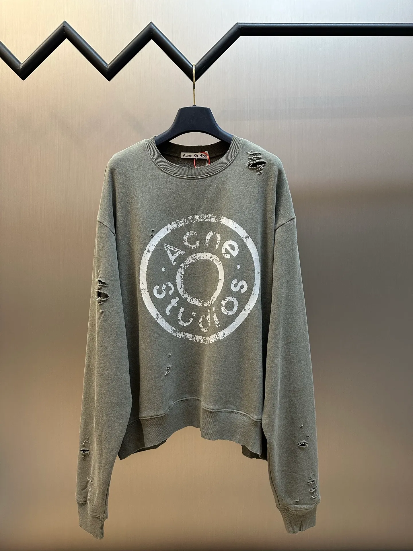 Ac Studios ripped distressed logo sweatshirt, custom dyed 1:1 gray green soft cotton sweatshirt material, the top fabric and terry bottom are the same color configuration, the market fabric In Stock has a different color on the top and bottom, which does not match the original! The minimum order quantity of fabric is 2 tons, and the fabric manufacturing process alone takes 45 days! The unruly soul of Ac Studios is engraved on the chest. The ingenious integration of hole elements and wanton swaying on the Gray canvas is a deliberate rebellion and a break away from the shackles of tradition. It is unique in the wave of the trend. It uses glue printing. The chest printing has been modified three times with the film screen. The glue liquid paint is used to print the pattern on the fabric, and the fabric is baked to fix the printing pattern. Many parts of the body of the garment are frayed and worn at regular intervals by purely artificial means, and marks are manually brushed to add texture and depth to the surface of the garment to imitate the texture of natural wear and tear. size：s m l xl
